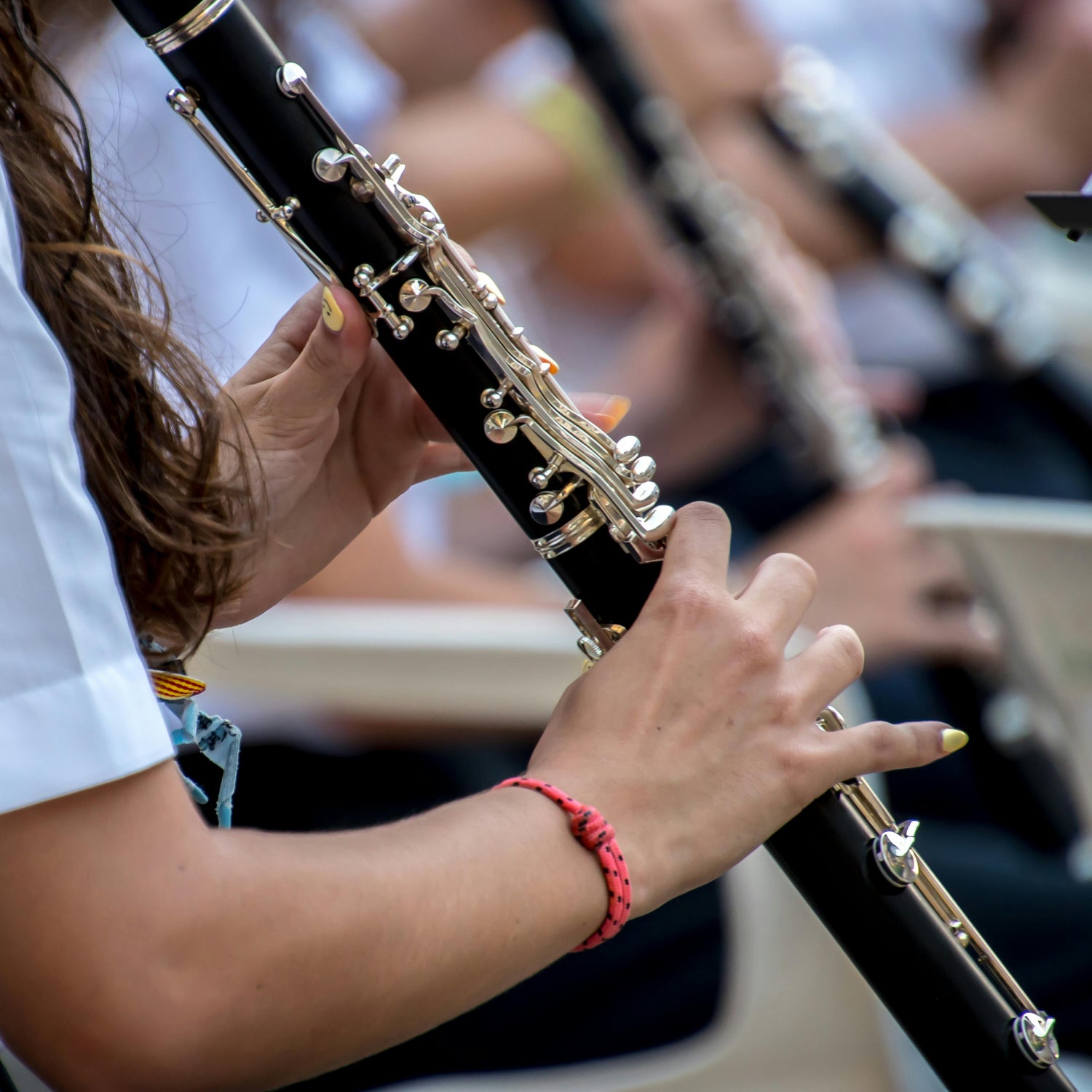 Person playing a clarinet with a blurred background of other musicians.
